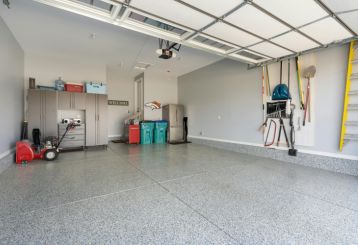 Spacious, organized garage in Cartersville, GA with epoxy flooring, overhead garage door, wall-mounted storage, and modern cabinets.