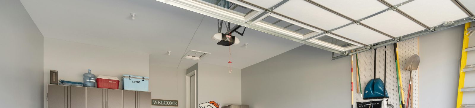 Spacious, organized garage in Cartersville, GA with epoxy flooring, overhead garage door, wall-mounted storage, and modern cabinets.