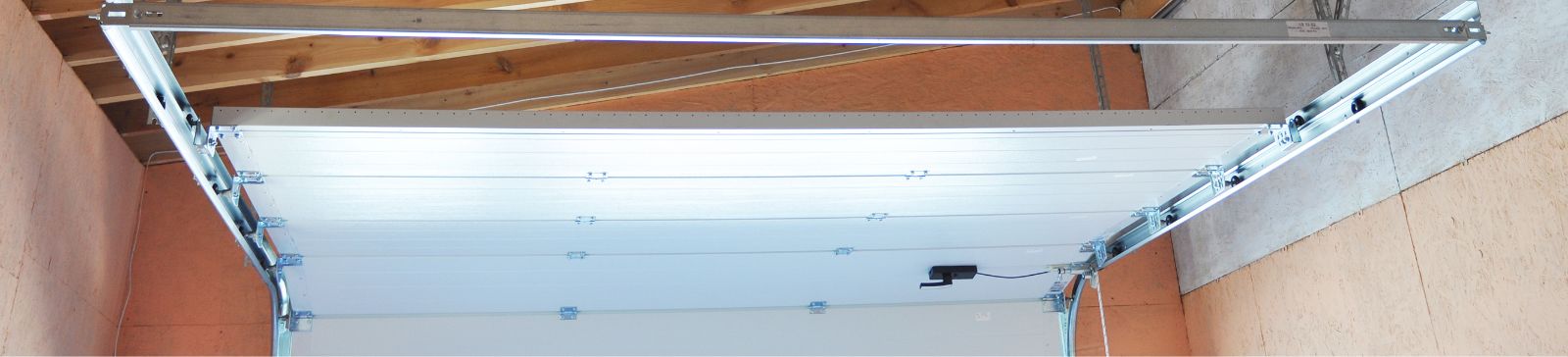 Interior view of a garage showing newly installed tracks and a partially open garage door, illustrating proper garage door assembly and maintenance in Cartersville, GA.