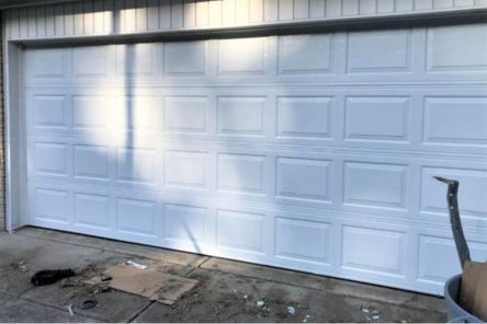 Wide shot of a modern white garage door fully installed on a beige home in Adairsville, GA, with a clear driveway and neat landscaping.