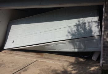 White garage door in Cassville stuck at an angle, visibly off track and unable to open or close properly.