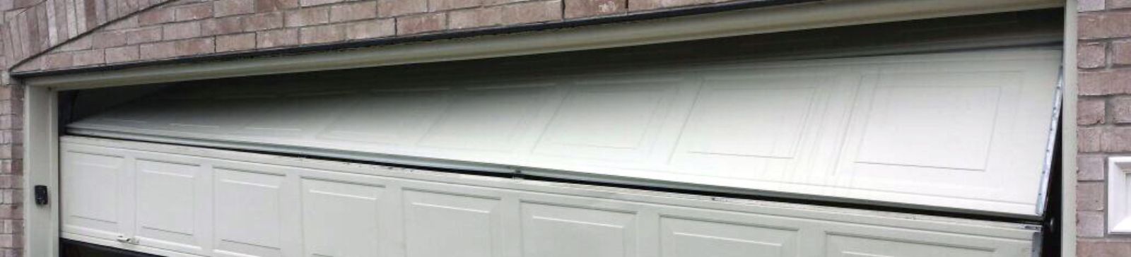 Garage door in Cassville completely dislodged from its tracks and partially collapsed onto the driveway, showing extensive misalignment.